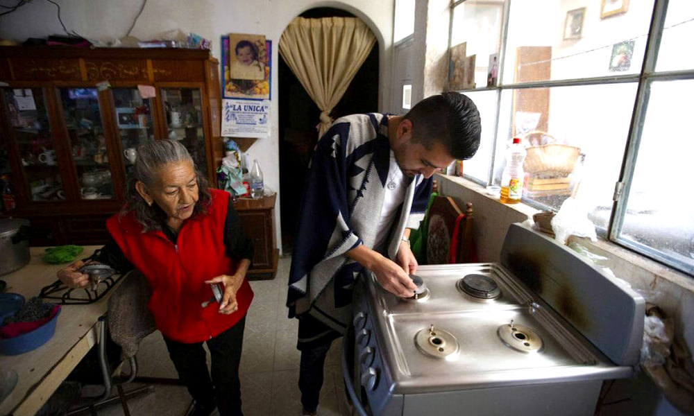 Juan Antonio Salas ayuda a limpiar la estufa de Cleotilde Borja, uno de sus pacientes recuperados por COVID-19
